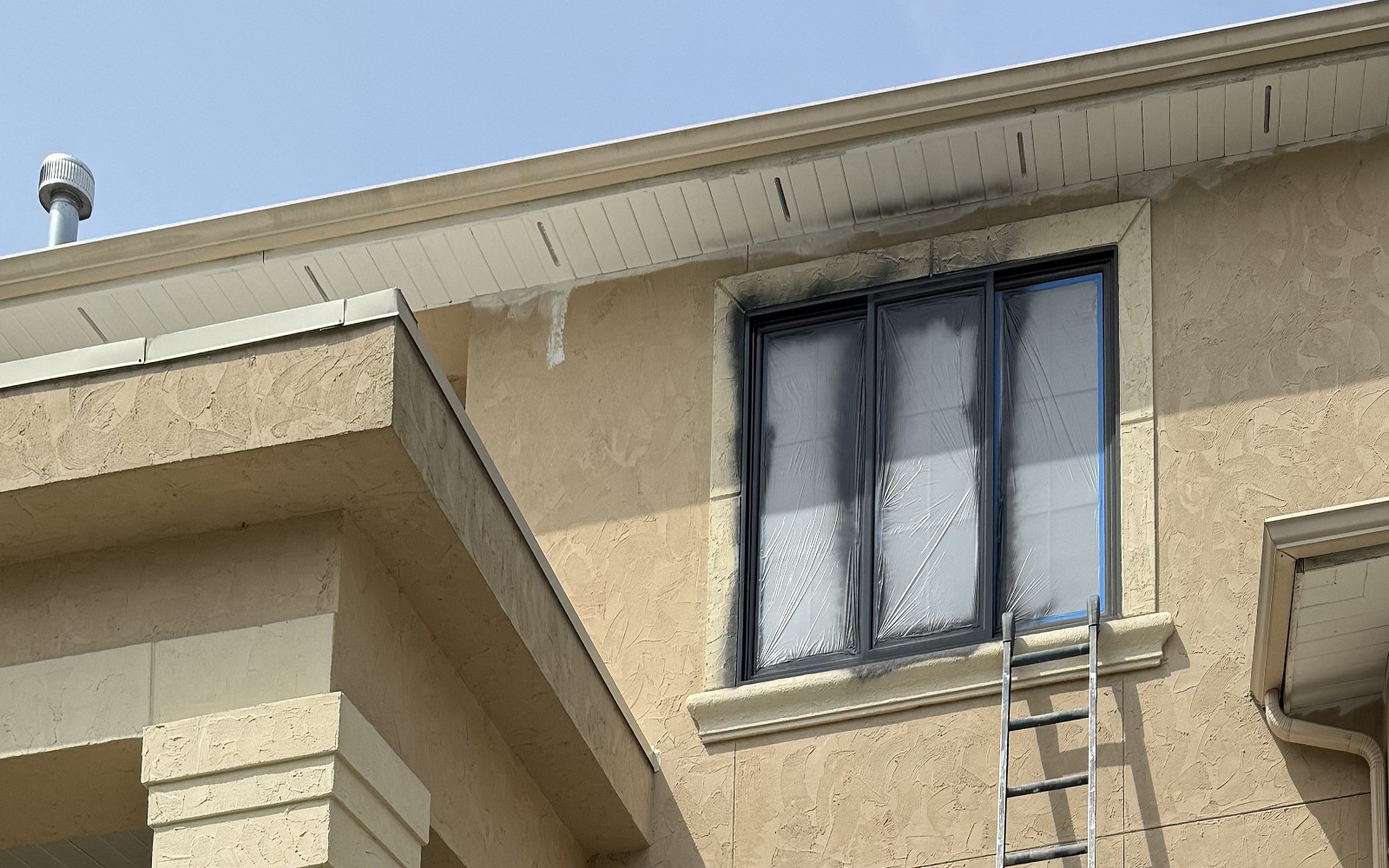 Upper entry elevation of a large stucco residence during preparation before the finish color