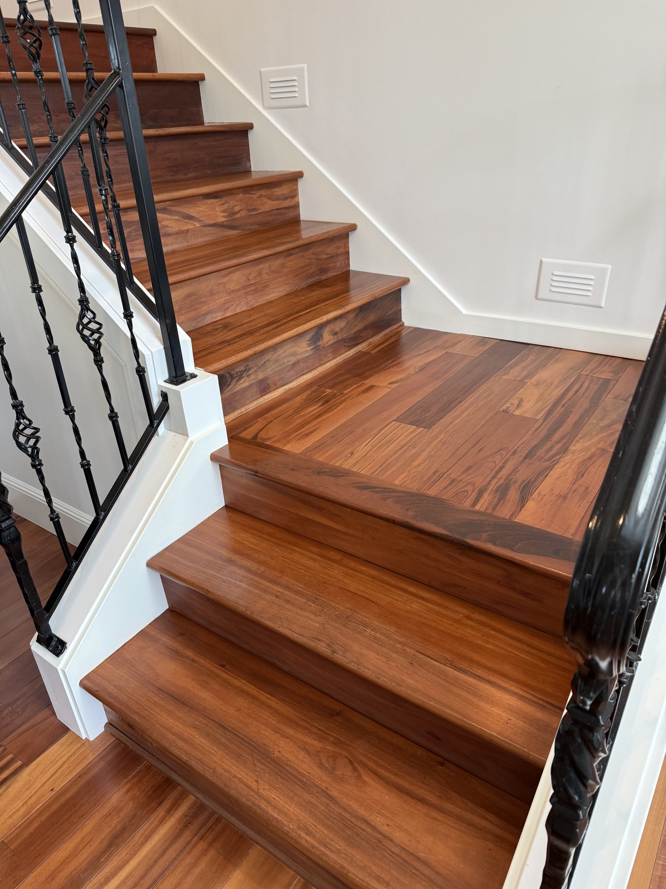 Finished hardwood staircase with white trim and black iron railing