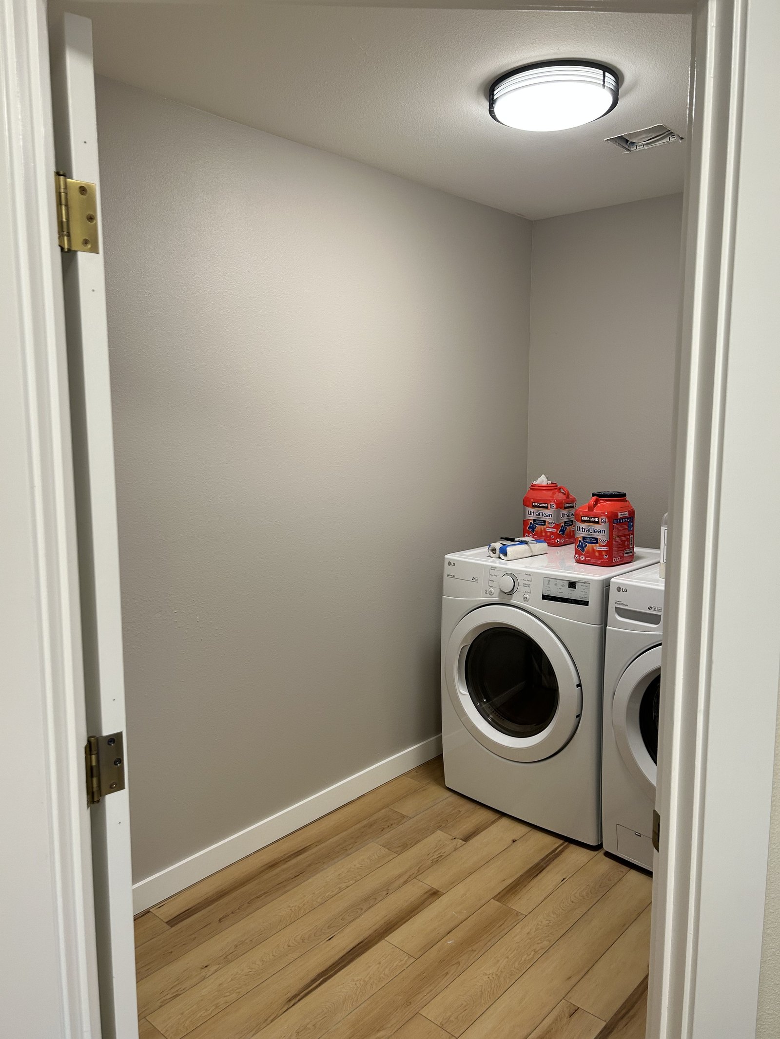 Completed laundry room with soft gray walls, white trim, and natural wood flooring