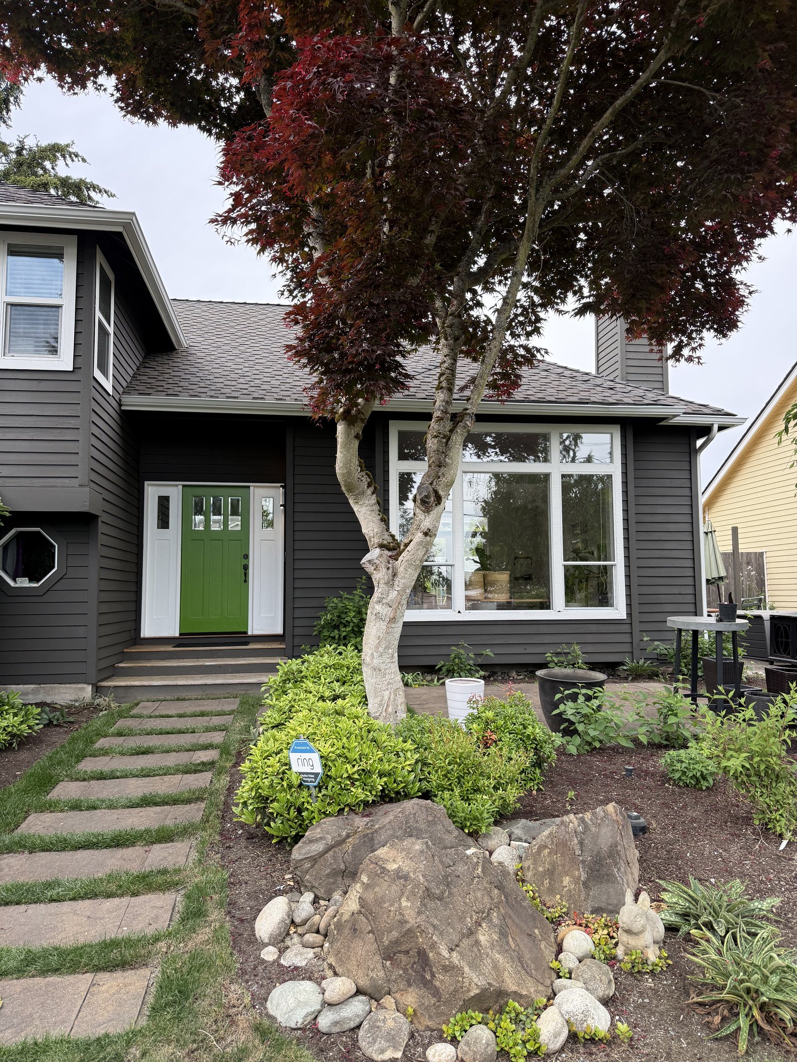 Completed charcoal residence with white trim and a green entry
