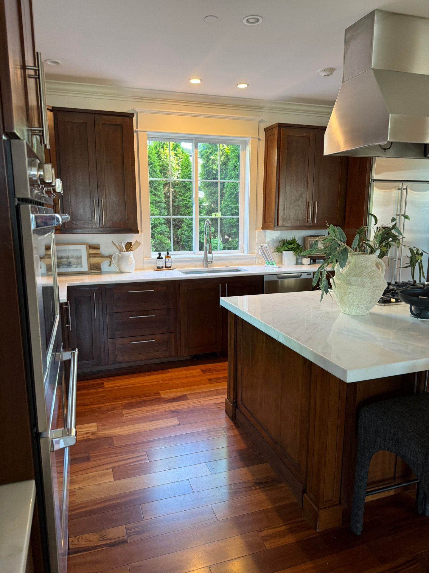 Completed kitchen with rich stained cabinetry, crown molding, and bright stone surfaces